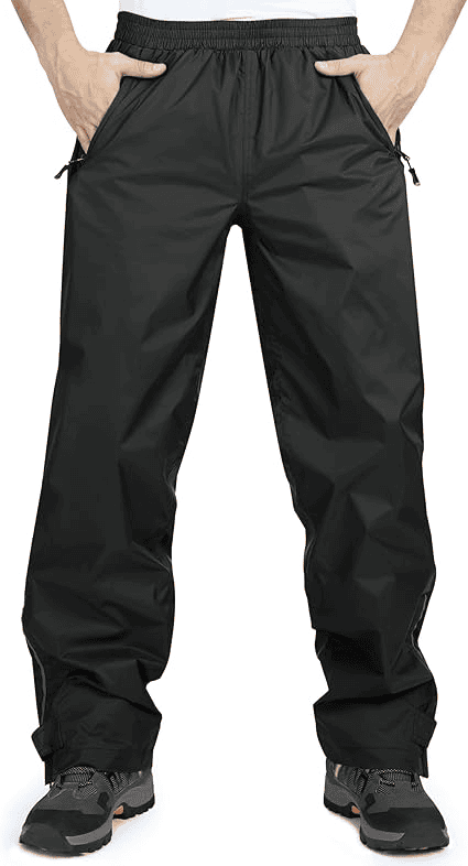 10 Best Men’s Waterproof Hiking Trousers for Rainy and Muddy Conditions 1 A Black waterproof rain pants with an elastic waistband, zippered side pockets, and adjustable ankle cuffs, worn over shoes with hands in pockets that is one of the 10 Best Men’s Waterproof Hiking Trousers for Rainy and Muddy Conditions